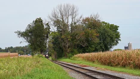 A-View-of-a-Restored-Antique-Steam-Passenger-Train-Approaching-Thru-a-Cut-in-the-Corn-Fields,-Blowing-Smoke-and-Steam-on-a-Sunny-Day