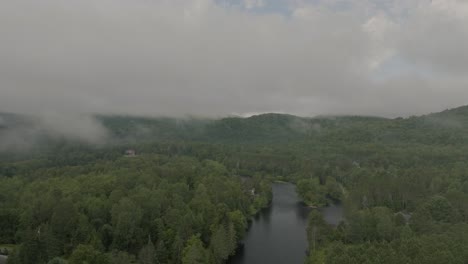 Drone-flying-through-a-beautiful-foggy-mountain-top-landscape,-over-a-river