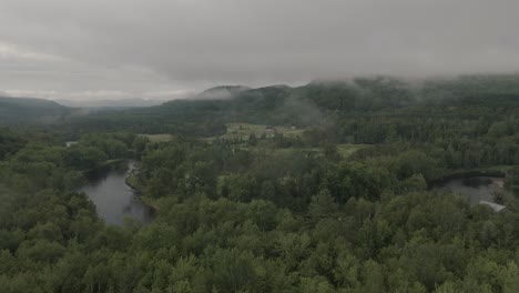 Drone-flying-through-a-beautiful-foggy-mountain-top-landscape,-over-a-golf-course