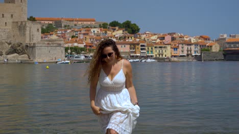 Cute-girl-walking-slowly-out-of-the-bay-of-Collioure-and-playing-with-her-hair,-France