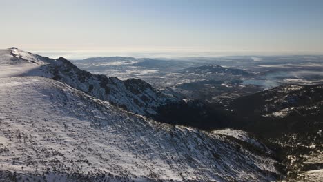 Endlose-Wilde-Schneebedeckte-Bergkette-Und-Ein-Wasserreservoir-Am-Horizont