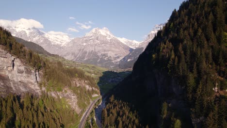 Aerial-drone-footage-pushing-in-and-raising-down-at-entrance-of-Swiss-mountain-village-Grindelwald,-picturesque-views-of-Swiss-Alps