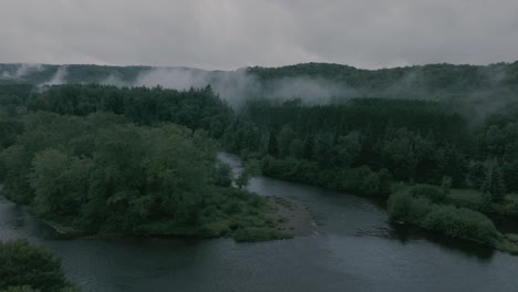 Drone-flying-through-a-beautiful-foggy-mountain-top-landscape,-over-a-river-2