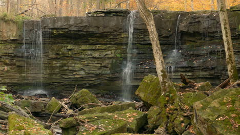 Waterfall-on-majestic-geological-rock-structure-in-autumn-forest,-static-view