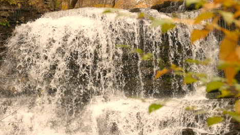 Powerful-autumn-forest-waterfall-splashing-down-rocky-landscape,-static-view