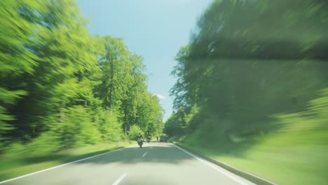 A-hyperlapse-of-driving-through-a-picturesque-German-forest-during-the-day,-being-overtaken-by-motorbikes