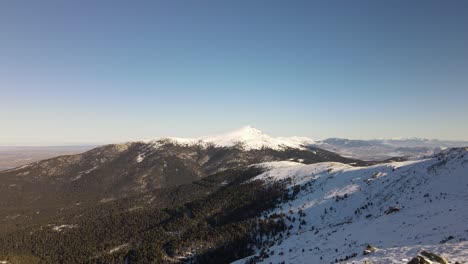 Despegue-De-Un-Dron-Aéreo-Desde-Un-Camino-Nevado-Que-Revela-Una-Interminable-Cadena-Montañosa-Salvaje-Cubierta-De-Nieve