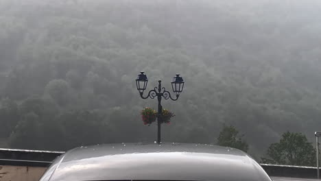 Close-up-shot-of-rain-and-hail-hitting-a-car-during-the-day-in-the-street-of-gavarnie-gedre-village-in-the-wild-pyrenees-mountain-national-parc