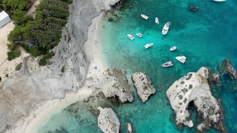 Drone-capture-shows-the-Tremiti-Island-cliff-overlooking-the-Adriatic-Sea's-turquoise-waters,-which-are-crowded-with-boats-and-yachts