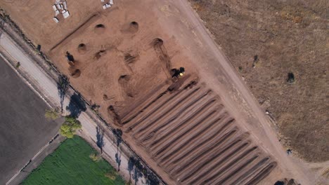 Slow-aerial-rotation-of-yellow-tractor-working-on-a-compost-farm-in-Mexico