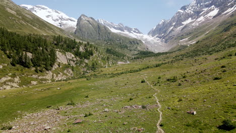 Luftbild,-Das-Im-Sommer-Durch-Ein-Bergtal-Mit-Schneebedeckten-Bergen-Im-Hintergrund-Vorrückt