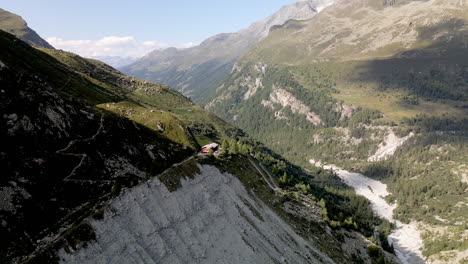 Vista-Aérea-De-Un-Refugio-De-Montaña-En-La-Cima-De-La-Montaña-Rodeada-Por-El-Bosque-En-Zinal,-Suiza