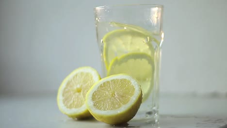 Schneiden-Sie-Zitronenfrüchte-In-Einem-Glas-Wasser-Auf-Dem-Tisch-Mit-Stockvideos-Mit-Weißem-Hintergrund