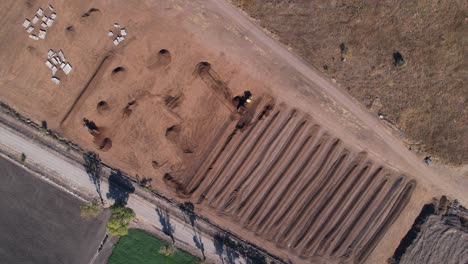 Aerial-of-yellow-tractor-dropping-compost-mixture-into-a-field