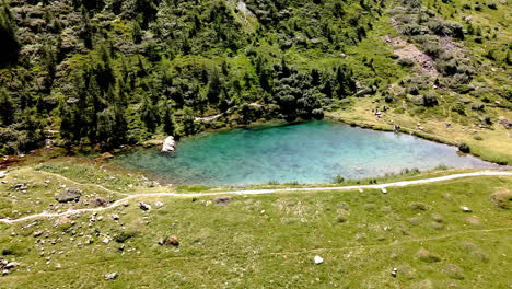 Aerial-view-circular-move-spinning-around-a-mountain-lake-of-turquoise-clear-water-in-the-summer