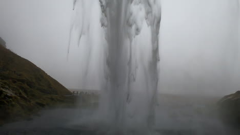 Toma-Cinematográfica-Detrás-De-La-Cascada-Islandesa-Seljalandsfoss-Y-Donde-El-Agua-Rompe-Con-Fuerza
