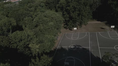 An-aerial-view-of-an-empty-black-and-white-basketball-court-in-a-park-on-a-beautiful-day