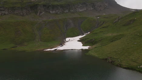 Lago-Bachalpsee-A-La-Sombra-De-Las-Nubes,-Toma-Hacia-Atrás-De-Una-Gran-Pala-De-Nieve