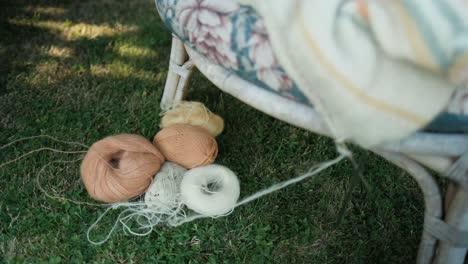 Knitted,-not-finish-sweater-left-on-chair-with-yarn-laying-on-the-grass