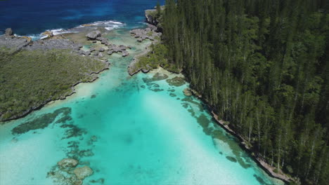 The-Natural-Pool-at-Oro-Bay-on-the-Isle-of-Pines-trickles-into-the-Pacific-Ocean---aerial-flyover