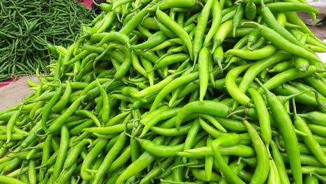 Close-up-top-view-of-freshly-harvested-green-chilies,-and-capsicum,-displayed-in-the-weekly-market-for-sale-in-Maharashtra-India