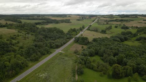 Aerial-shot-of-the-long-highway-with-driving-cars-surrounded-by-green-lush-trees-from-both-sides-2