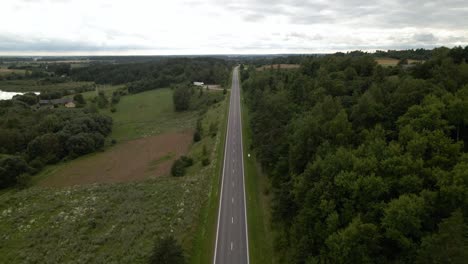 Aerial-shot-of-the-long-highway-with-driving-cars-surrounded-by-green-lush-trees-from-both-sides-1