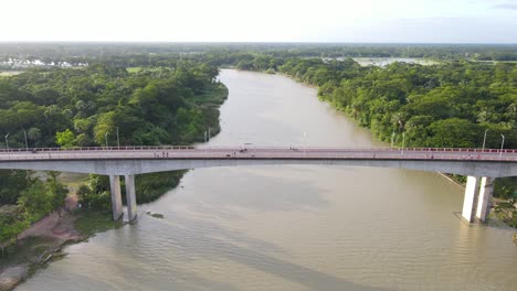 Muddy-water-of-river-with-concrete-bridge-leading-over,-aerial-view