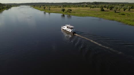 Toma-Aérea-De-Un-Ferry-Navegando-En-El-Río-Nemunas-Con-Hermosa-Naturaleza-Cerca-De-Kaunas,-Lituania-1
