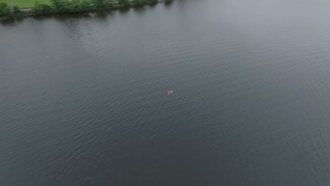 Bogenförmige-Drohnenaufnahme-Eines-Einzelnen-Schwimmers,-Der-In-Den-Ruhigen-Gewässern-Von-Loch-Lomond-Schwimmt
