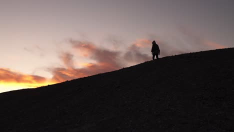 Silhouette-of-man-on-ridge-walking-against-sunset-sky,-Death-Valley