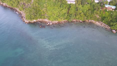 Dron-Aéreo-Panorámico-Lento-Sobre-Aguas-Azules-Tropicales-En-Tailandia-Con-Casas-En-La-Ladera-Verde-De-La-Montaña