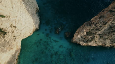 Dramatic-flip-aerial-drone-shot-over-rocks-in-a-blue-sea