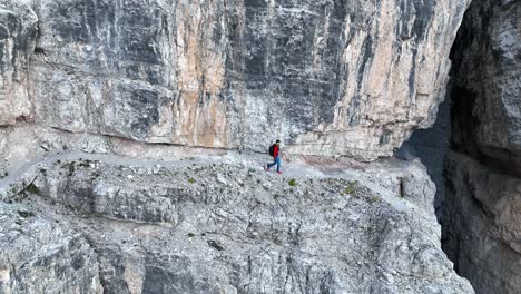 A-mountaineer-walking-along-an-exposed-hiking-trail-in-the-Dolomites-in-Italy
