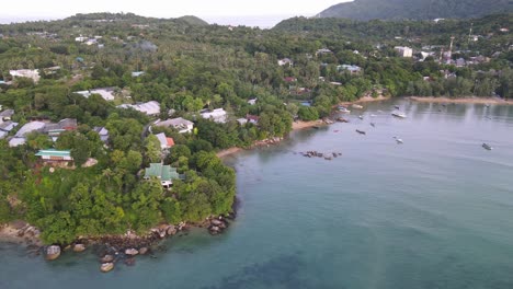 Drohne-Bewegt-Sich-Rückwärts-über-Tropisches-Blaues-Wasser-Mit-Grünen-Berghäusern-In-Thailand