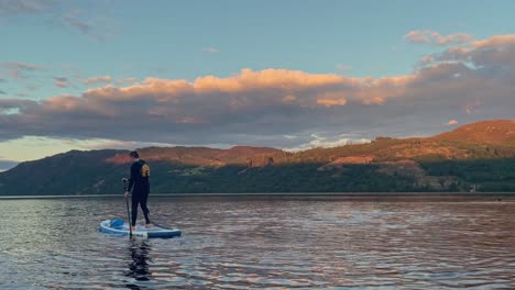 Macho-Joven-Remando-En-Un-Stand-Up-Paddleboard-En-Un-Pacífico-Loch-Lomond