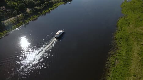 Aerial-shot-of-a-ferry-boat-sailing-on-river-Nemunas-with-beautiful-nature-near-Kaunas,-Lithuania