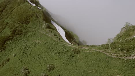 Vista-Cinematográfica-De-Una-Pareja-Caminando-Por-Un-Sendero-De-Montaña,-Moviéndose-Sobre-El-Borde-Superior-De-La-Colina