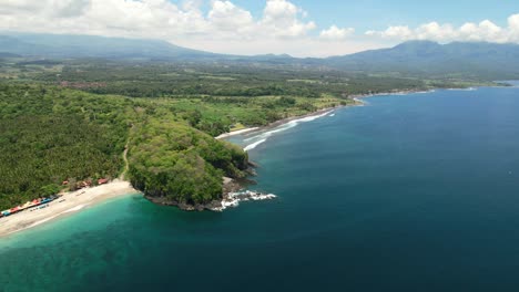 Wide-panoramic-aerial-view-of-east-Bali-coastline-at-Pantai-Prasi-with-blue-ocean-and-white-sand-beach-on-sunny-day