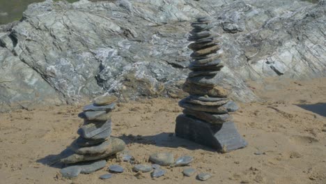 Rock-stacking-on-sandy-beach-blue-slate