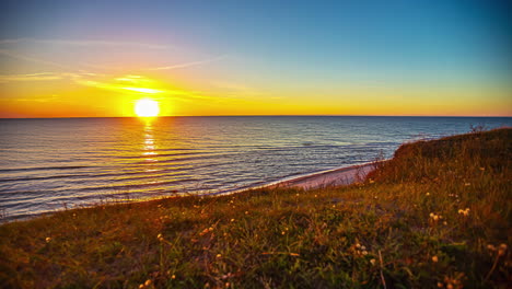Golden-sunset-on-the-horizon-of-the-ocean-with-gentle-waves-on-the-beach---time-lapse