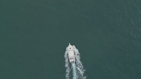 Aerial-establishing-shot-drone-following-a-small-boat-speeding-in-the-ocean-top-down-bird-eye-view