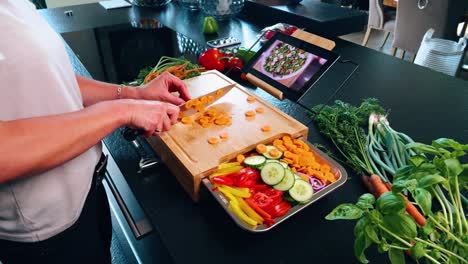 Cutting-board-with-knife-and-a-carrot-with-other-vegetables-and-a-tablet-with-recipes