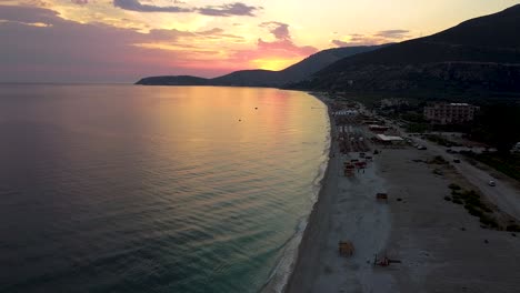 Sunset-on-the-beach-in-Albania,-with-the-sun-setting-behind-the-mountain