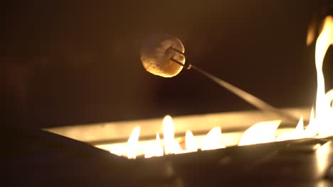 Tasty-white-marshmallow-on-skewer-roasting-over-gas-fire-pit