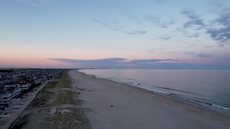 Aerial-view-from-a-drone-flying-over-an-Ocean-City,-New-Jersey-beach-at-dusk
