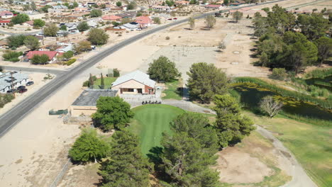 A-golf-course-green-in-a-desert-community---tilt-down-orbiting-aerial-view