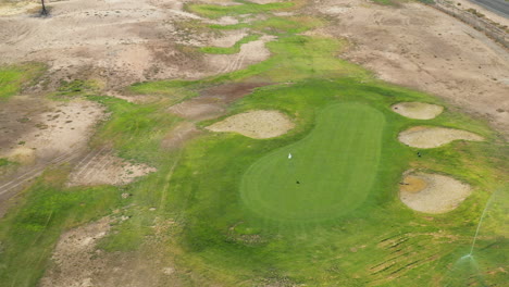 Hitting-the-ball-over-a-tree-and-landing-on-the-golf-course-green---aerial-view-from-the-golf-ball