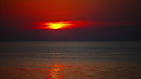 Beautiful-red-sun-setting-in-the-horizon-beyond-calm-waves---Hyperlapse