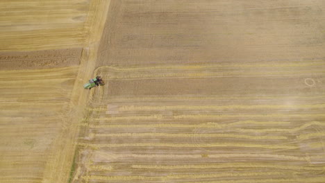 Aerial-top-down-shot-of-combine-harvester-on-large-wheat-field,-produced-pattern